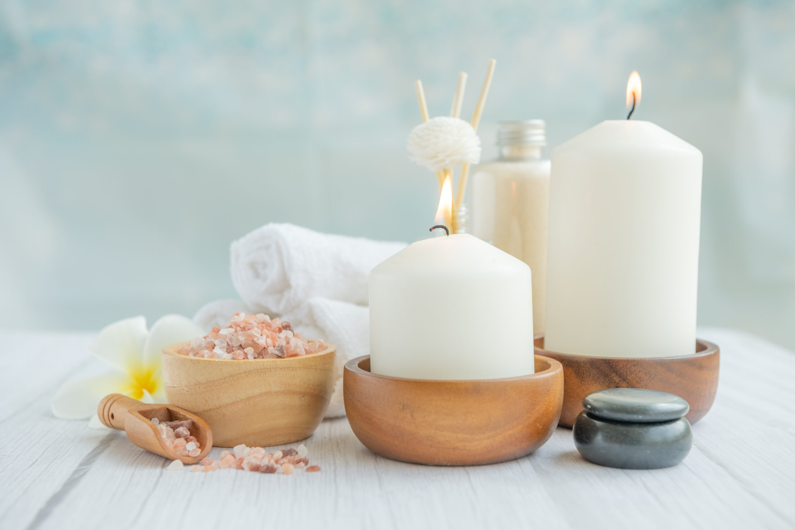 Natural relaxing spa composition on massage table in wellness center    with towels, flowers and salt, candle  on massage table in spa salon.